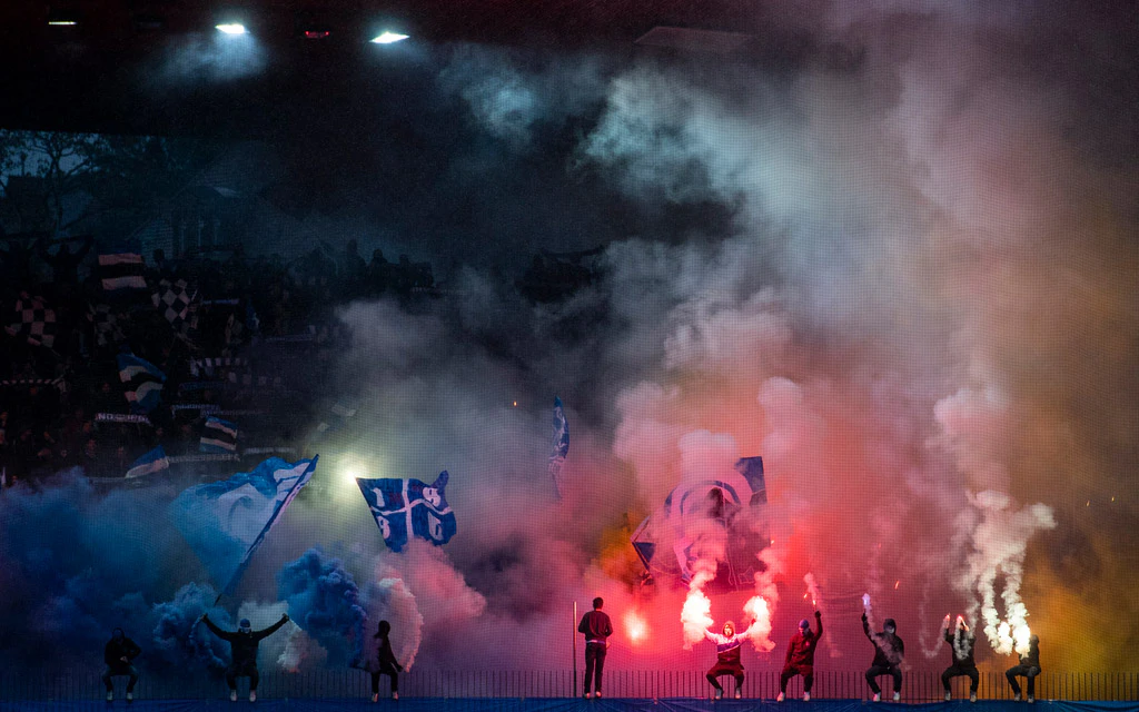 Tifosi accendono pezzi pirotecnici durante una partita di calcio.